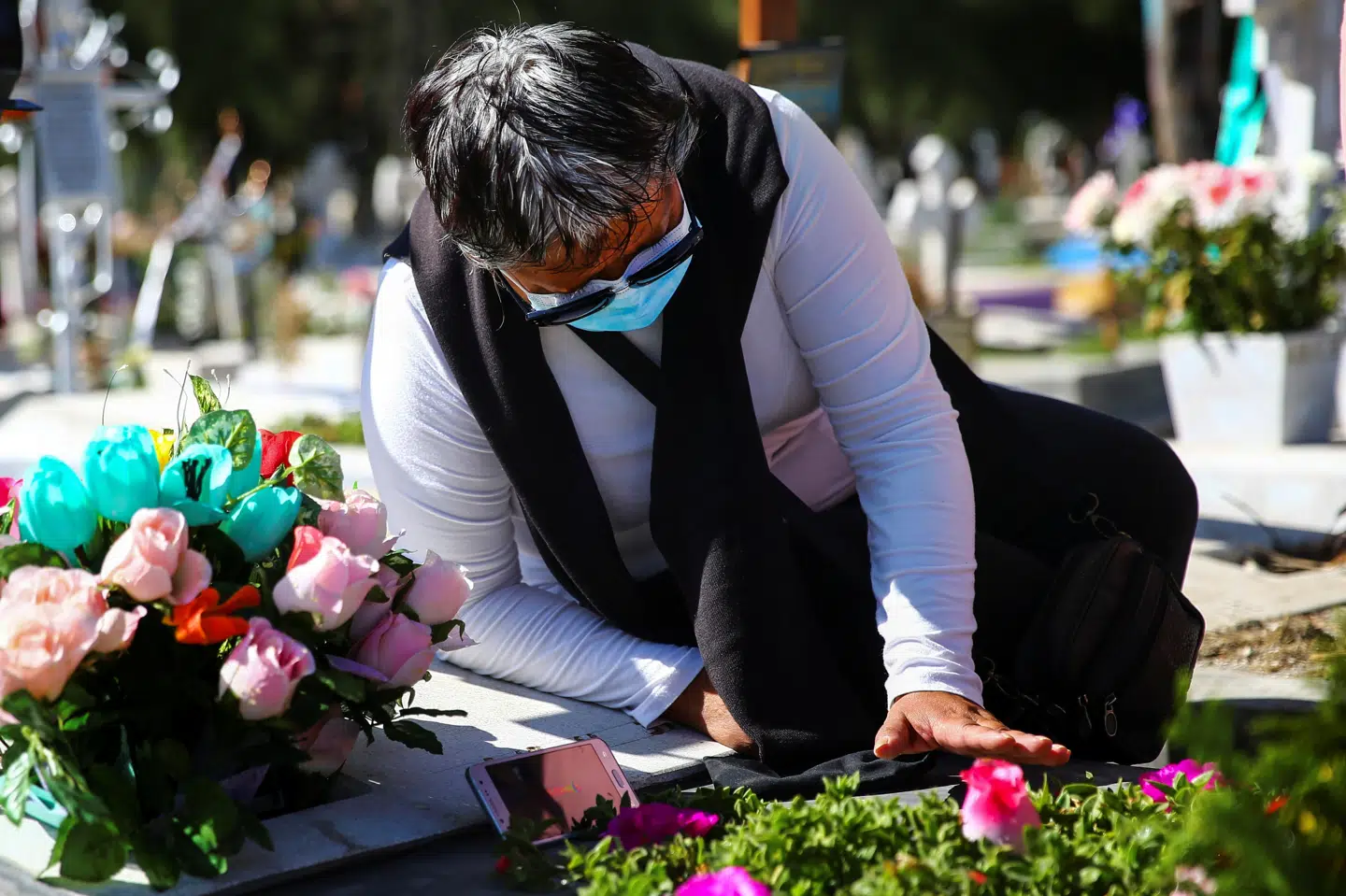 En mexicansk kvinde lægger blomster ved sin mors grav, efter at moren i august døde med covid-19. (Arkivfoto) Edgard Garrido/Reuters