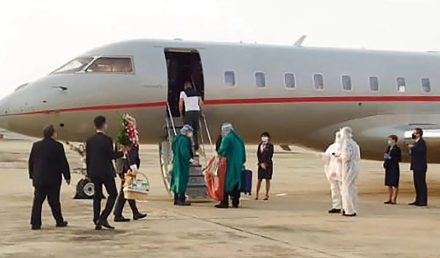 Peter Szijjarto forlader Bangkok lufthavn som den eneste passager på privatfluet, der fløj ham hjem til Ungarn onsdag. Folk i beskyttelsesdragter fra Thailand ser på.