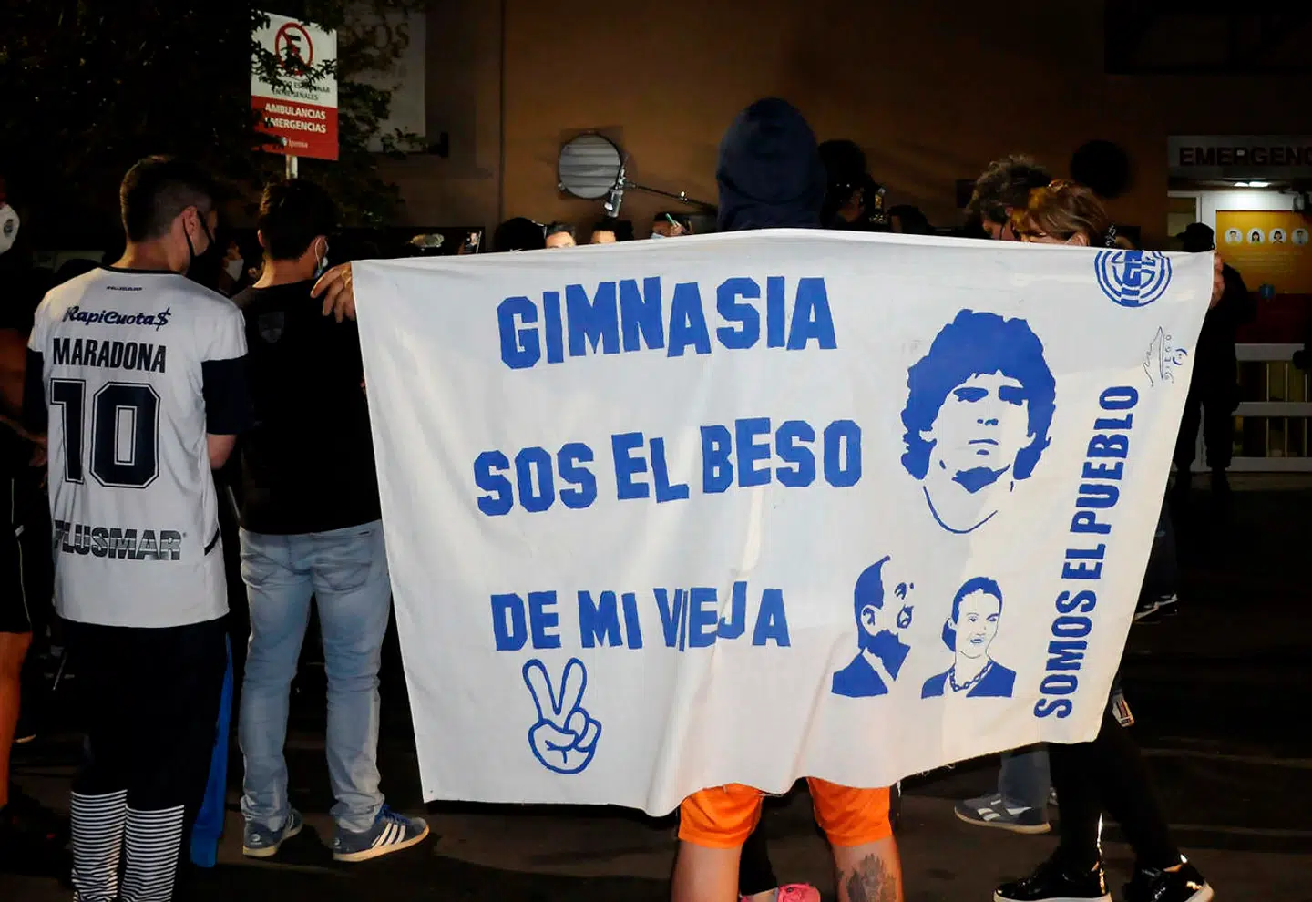 Handout picture released by Telam showing football fans listening to Leopoldo Luque (unseen), the personal physician of Argentine former football star and coach of Gimnasia y Esgrima La Plata Diego Maradona, giving a medical report outside the Ipensa clinic where Maradona has been admitted, in La Plata, Buenos Aires province, on November 2, 2020. - Though Luque gave no details of Maradona's condition, he said his patient would undergo a series of medical check-ups. (Photo by Eva Cabrera / TELAM / AFP) / Argentina OUT / RESTRICTED TO EDITORIAL USE - MANDATORY CREDIT AFP PHOTO / NOTICIAS ARGENTINAS - NO MARKETING - NO ADVERTISING CAMPAIGNS - DISTRIBUTED AS A SERVICE TO CLIENTS