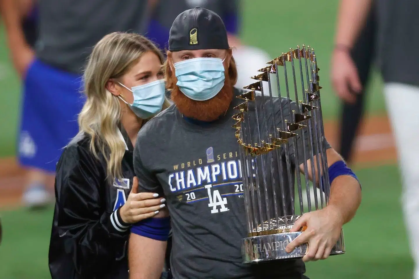 Justin Turner ses her med MLB trofæet i sin ene hånd og konen på sin anden side.