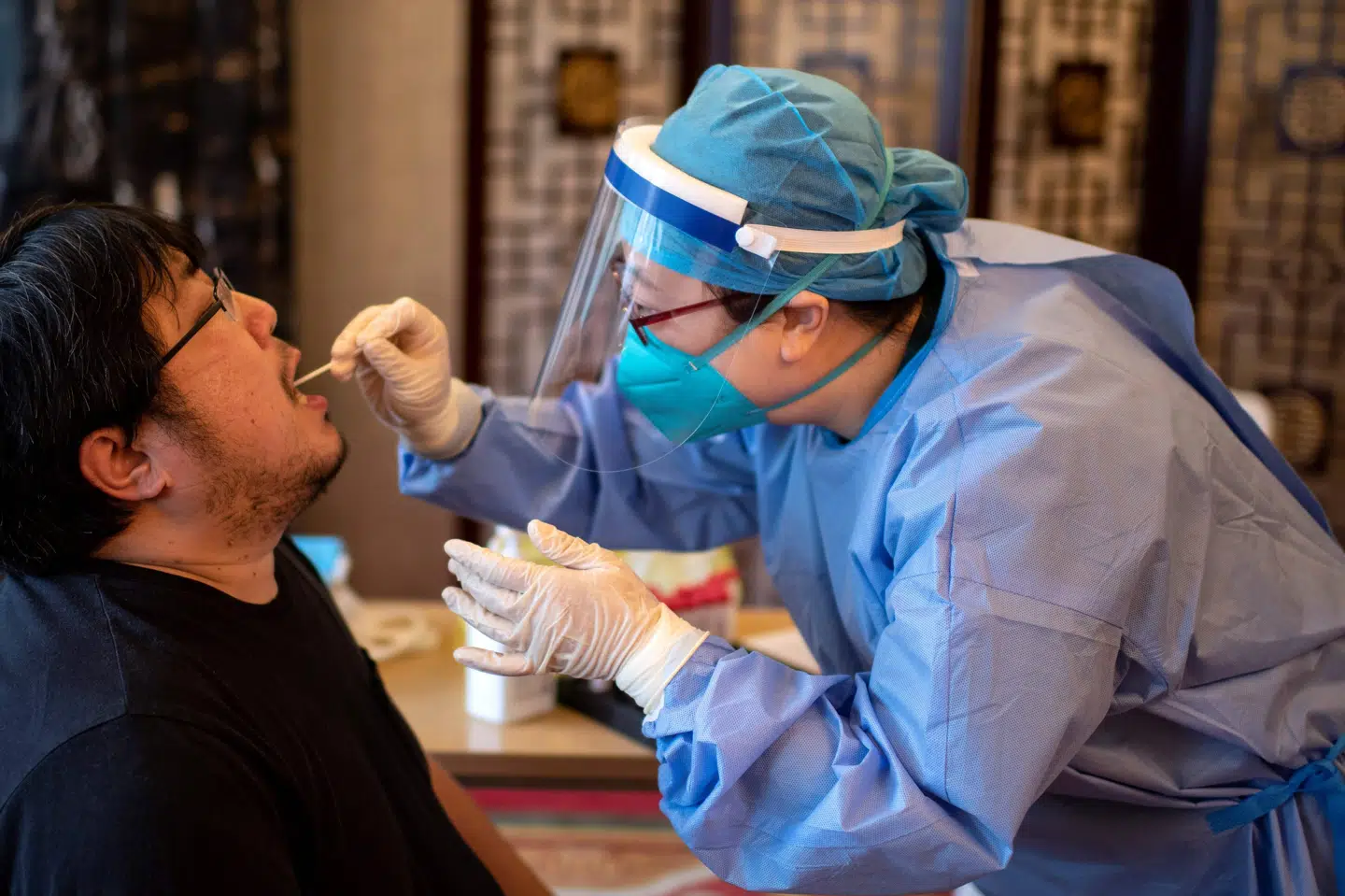 En sundhedsarbejder tester for coronavirus i Beijing. Kina vil de kommende dage teste ni millioner mennesker på fem dage i byen Qingdao efter et mindre virusudbrud i byen. Noel Celis/Ritzau Scanpix