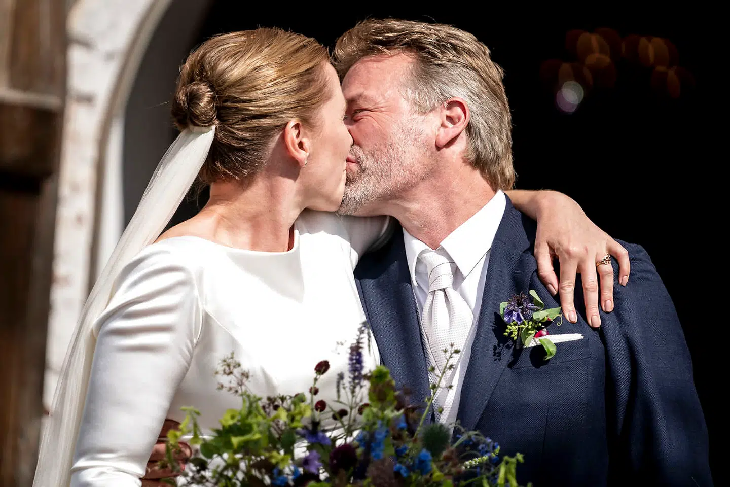 Mette Frederiksen og Bo Tengberg kysser foran Magleby Kirke, efter at de er blevet gift.