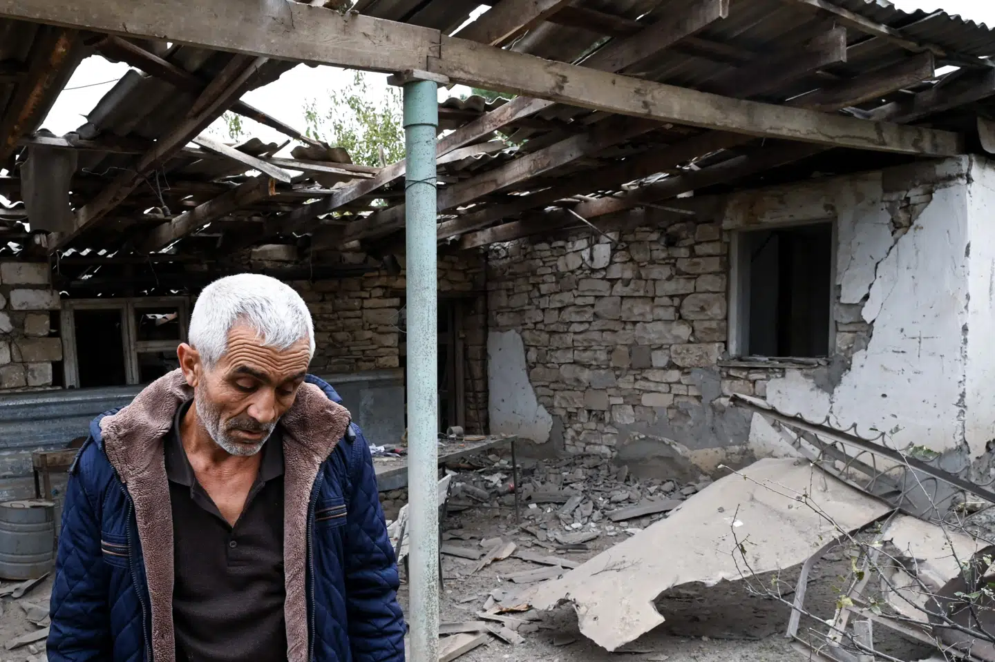 En mand på en gårdsplads torsdag foran hans brors hus, der er ødelagt under et granatangreb mod byen Martuni i enklaven Nagorno-Karabakh. Det er sket under kampe mellem armenske og aserbajdsjanske styrker. -/Ritzau Scanpix