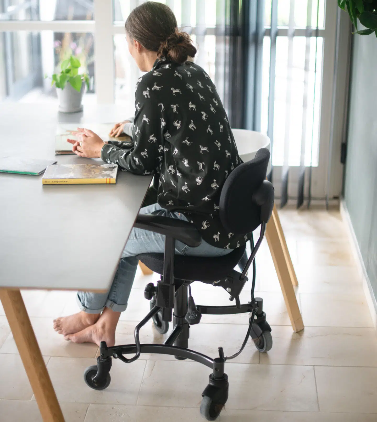 Karla bruger en stol med hjul på, når hun sidder ved spisebordet, så hun så skal bruge færre kræfter, når hun skal skubbe sig væk fra bordet. Foto: Michael Nørgaard/Byrd.