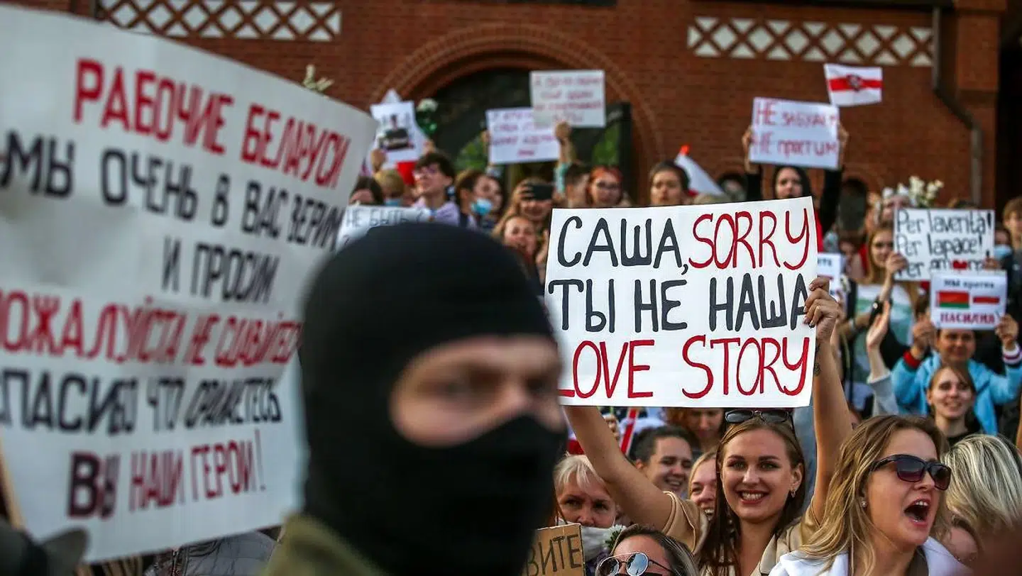 En maskeret mand foran kvindelige demonstranter i Hviderusland.