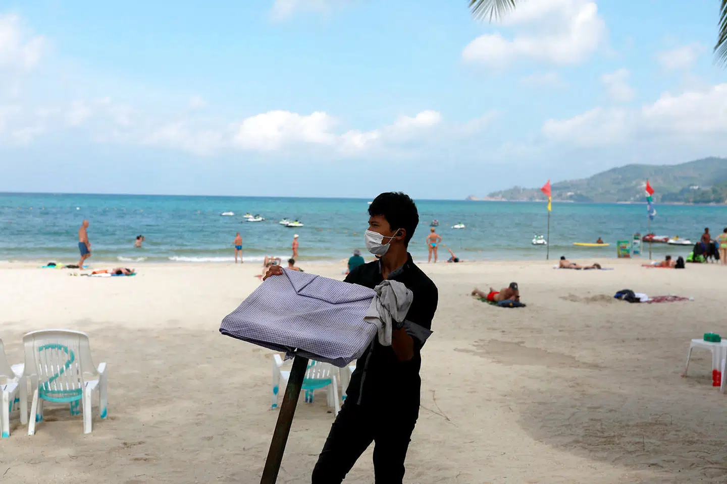 En tjener arbejder på stranden i Phuket i begyndelsen af marts, hvor der stadig var turister i landet. Reuters.