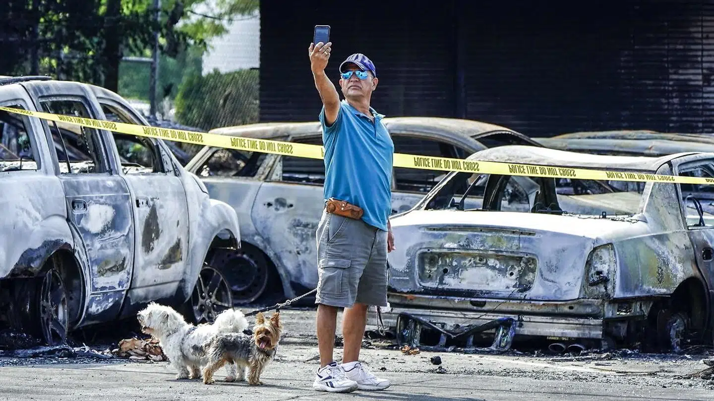En mand tager en selfie ved siden af udbrændte biler efter demonstrationerne.