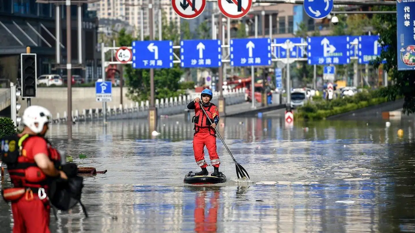 Et medlem af Chongqings beredskab på et paddleboard for at forsere vandmasserne i byen.