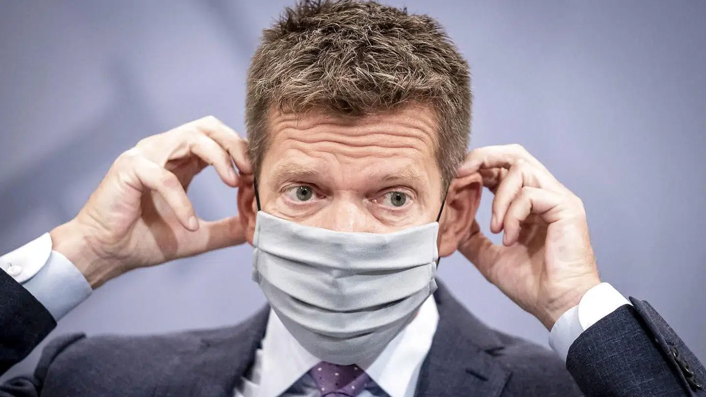 Sundhedsstyrelsens direktør Søren Brostrøm demonstrerer, hvordan man tager mundbind på under pressemødet.