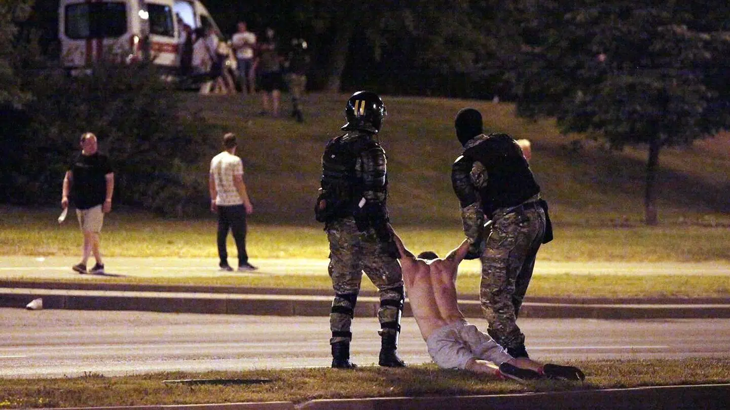 Kampklædt politi bærende på en demonstrant i Minsk søndag aften.