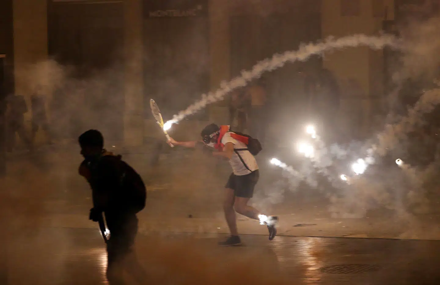 Flere demonstranter bruger tennisketsjere til at undvige det, der bliver kastet både af deres egne og politiet.