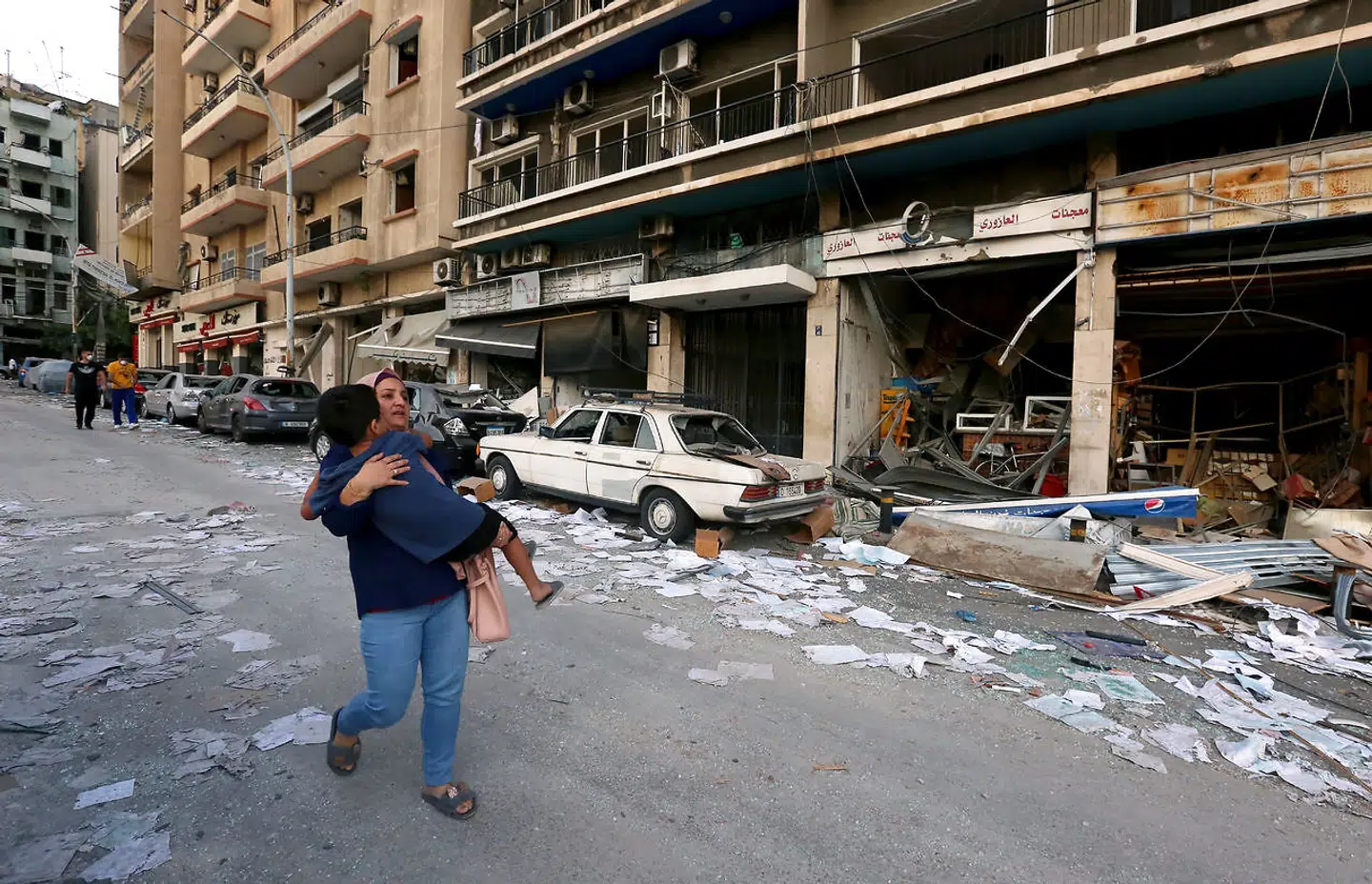 En kvinde løber med sin barn i armene. Væk fra ødelæggelserne fra eksplosionen i Beirut. REUTERS/Aziz Taher.