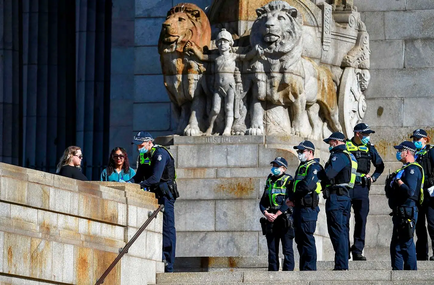 Politiet uddeler bøder til to kvinder, der ikke bærer ansigtsmasker, i Melbourne 31. juli 2020.