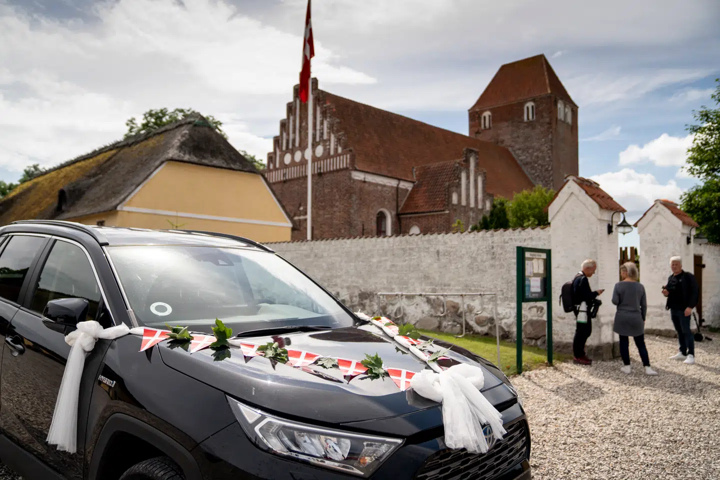 Bryllupskareten her parkeret foran Magleby Kirke på Møn. Her er flaget hejst til vejrs.