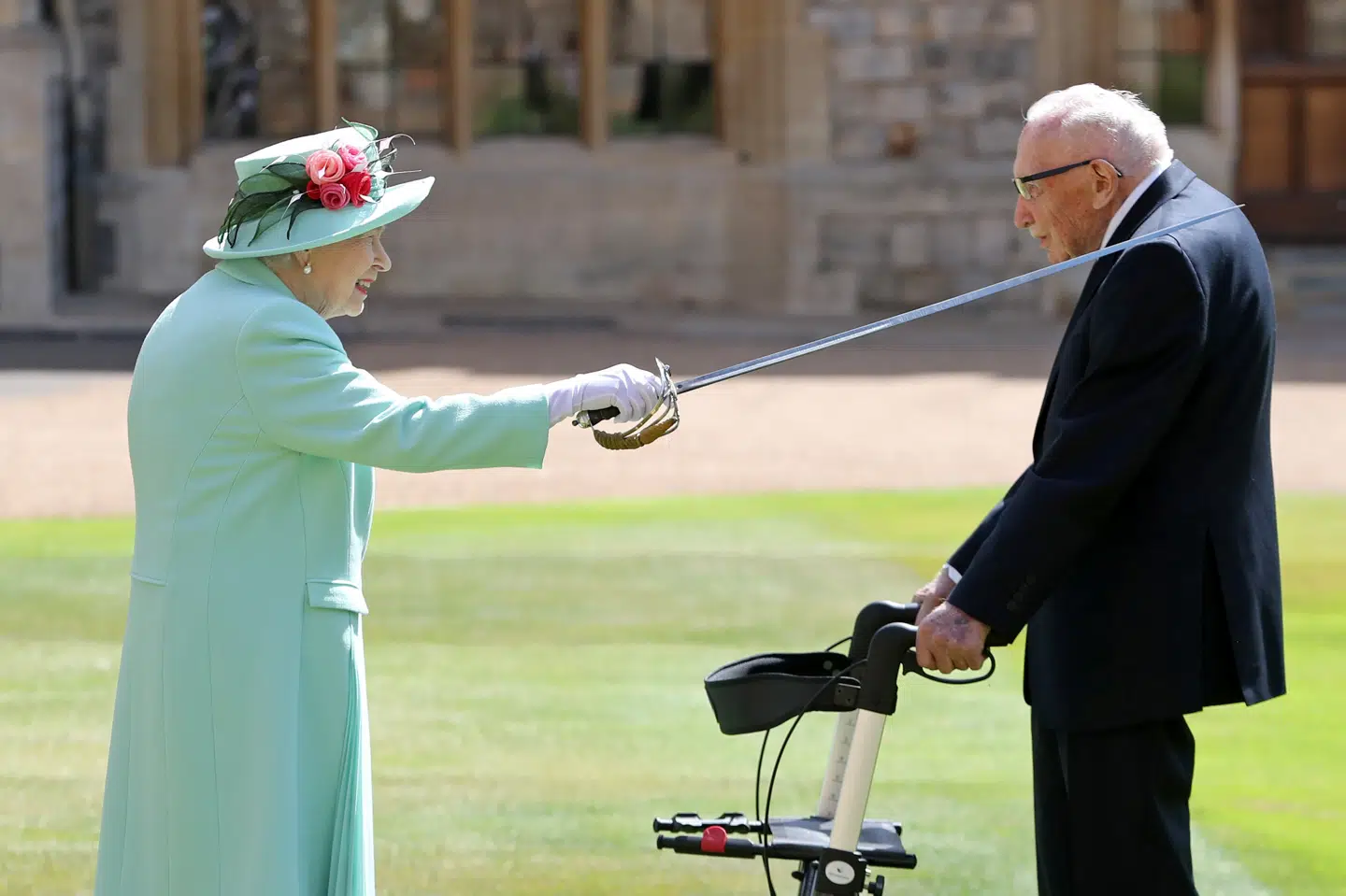 Den britiske dronning Elizabeth slog fredag den 100-årige krigsveteran Tom Moore til ridder for hans indsamling under coronakrisen. Pool/Reuters
