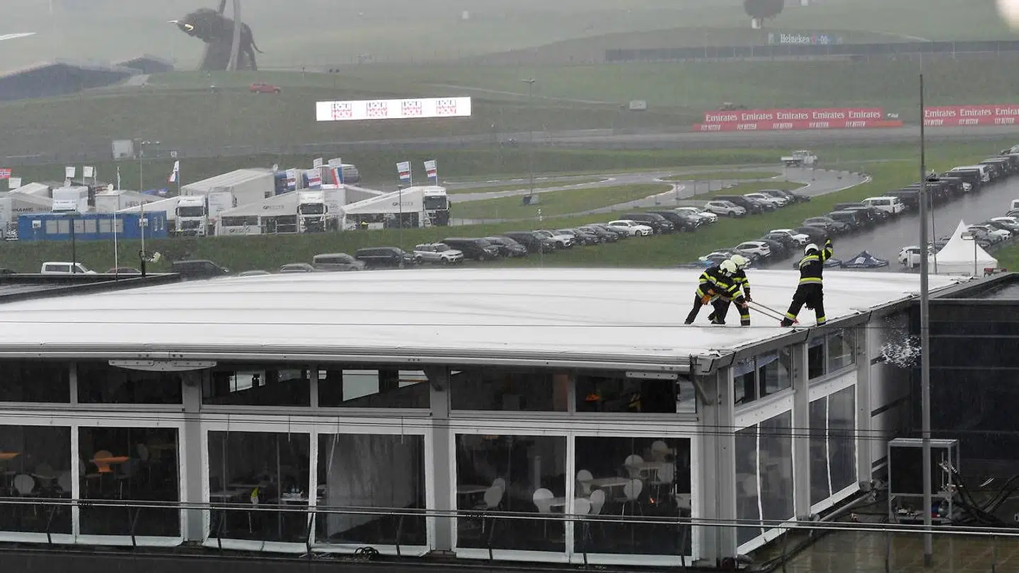 Brandfolk fejer vand af et tag efter de kraftige regnskyl, der ramte Red Bull Ring i Spelberg, Østrig.