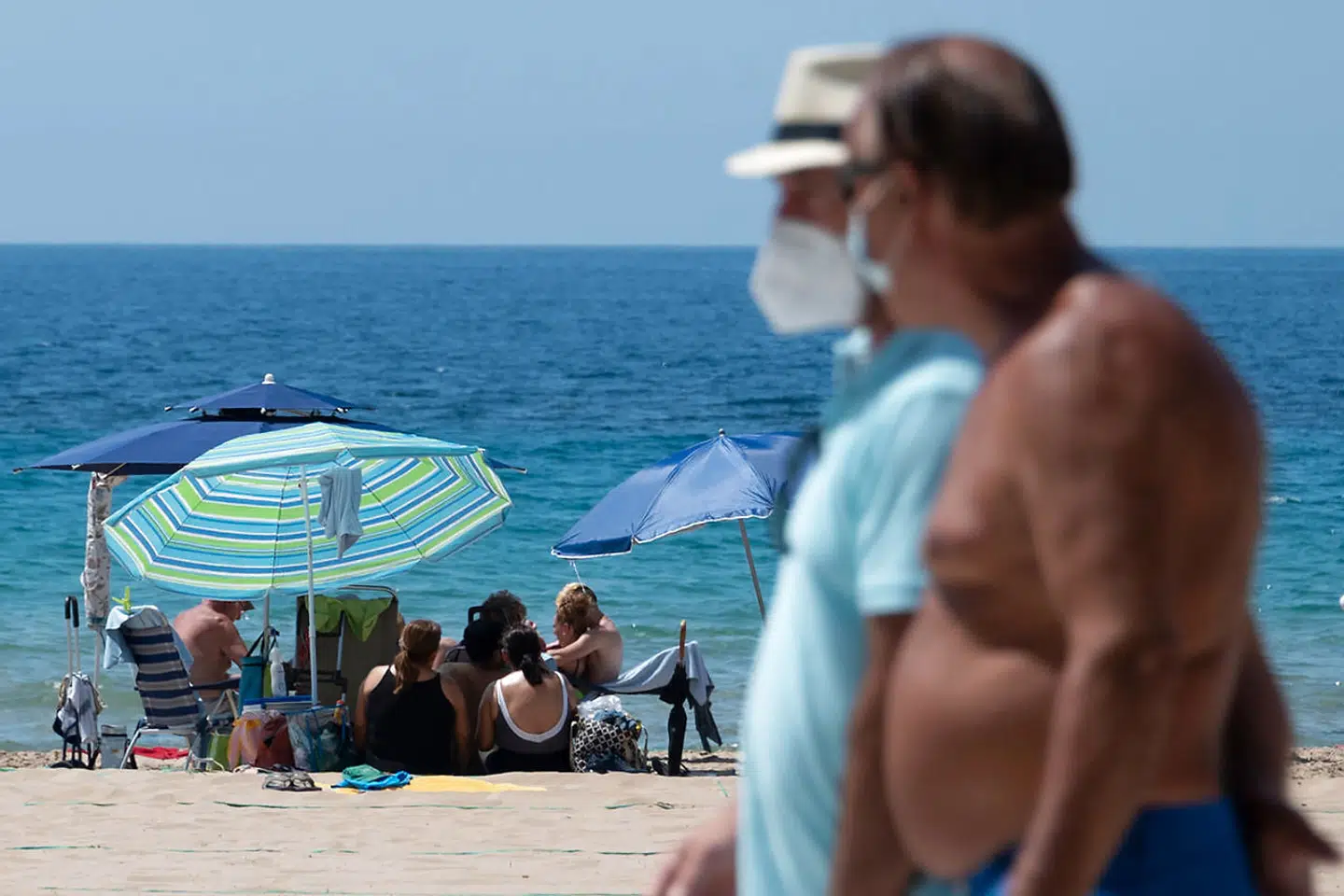 Også i Spanien bærer strandgæster corona-mundbind.