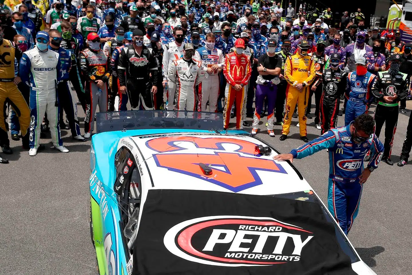 Bubba Wallace er tydeligt berørt over, at de andre kørere stiller sig op ved ham.