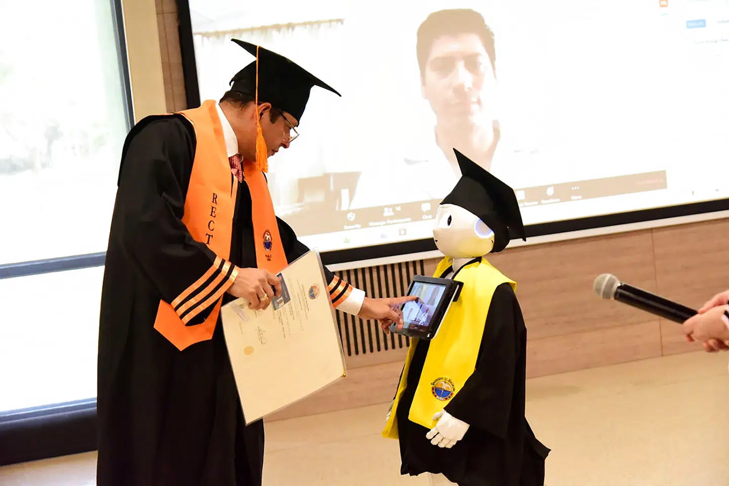 Rektor på universitetet i Magdalena, Colombia, uddeler eksamensbeviser under en online dimissionsceremoni med hjælp fra en robot, hvor de studerende er med på videosamtale. Det skete 25. marts for at mindske smitten af coronavirus.