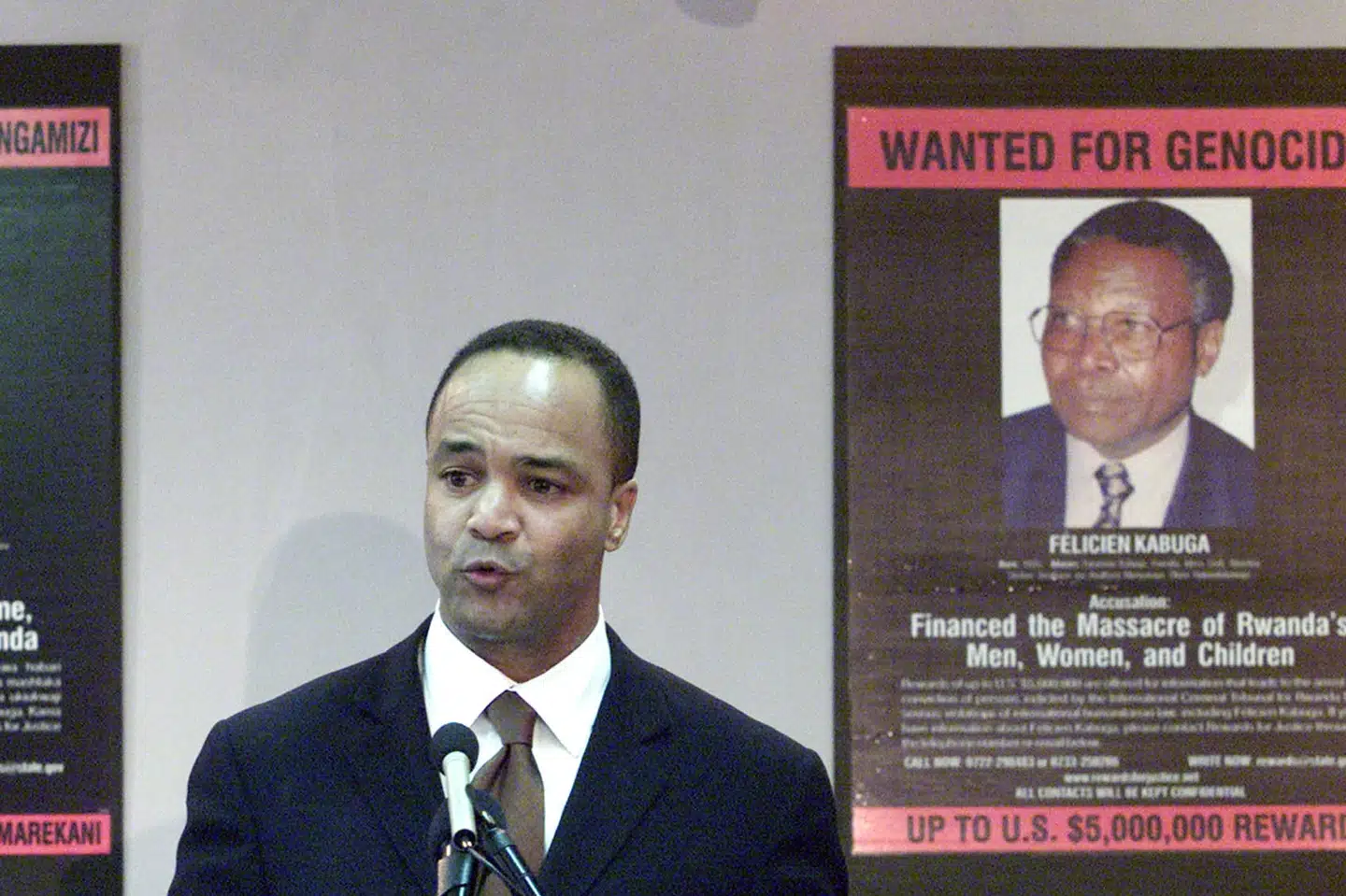 Den daværende amerikanske ambassadør for krigsforbrydelser Pierre-Richard Prosper i 2002 ved siden af en plakat for den stærkt eftelyste rwandiske krigsforbryder Felicien Kabuga. Først lørdag lykkedes det fransk politi at anholde Kabuga. George Mulala/Reuters