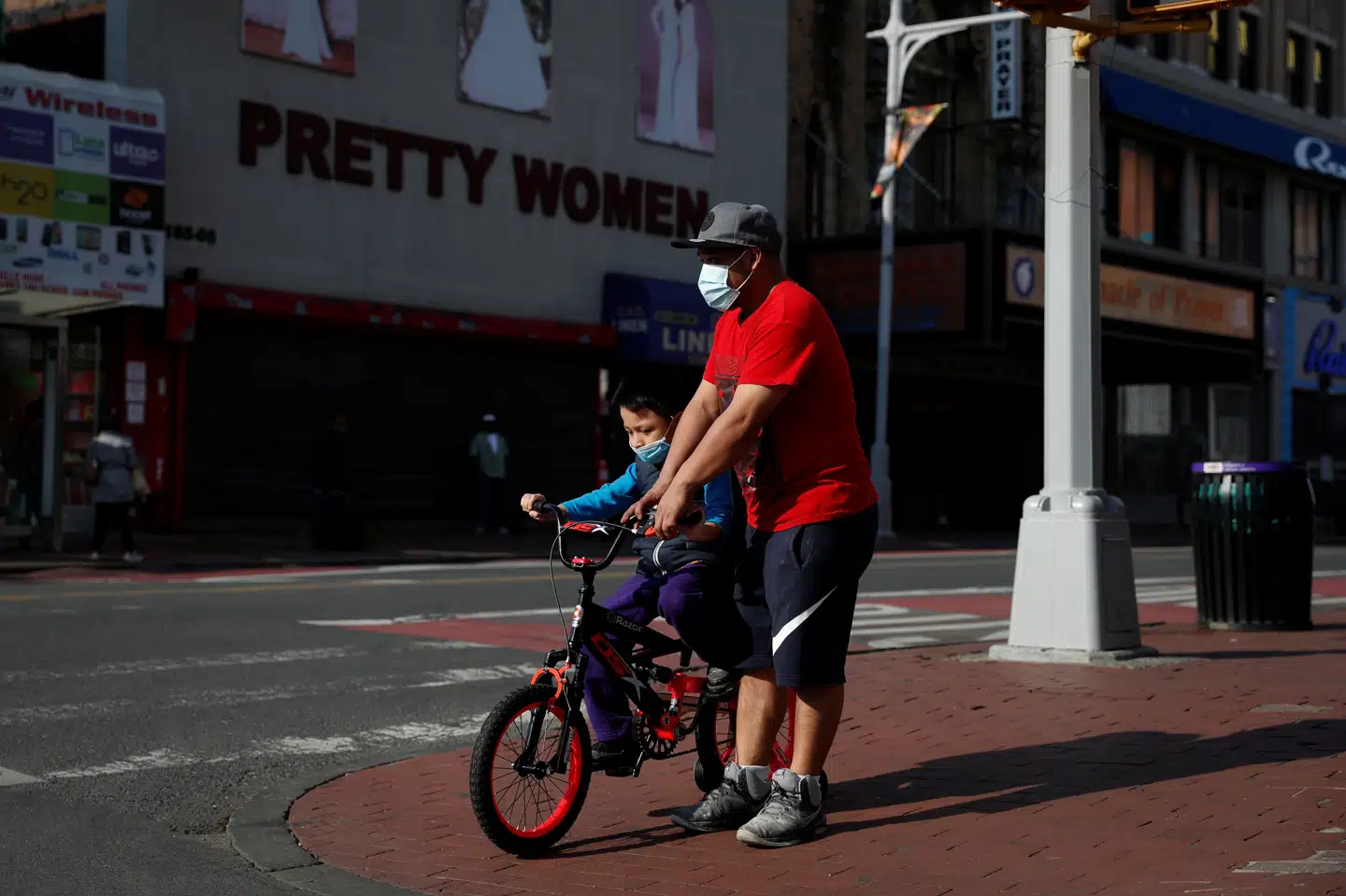 En mand hjælper en dreng med at holde balancen på cykel i bydelen Queens i New York. Delstaten er den hårdest ramte af USA's 50 delstater. Fredag melder guvernør Andrew Cuomo om 216 registrerede dødsfald blandt coronasmittede. Det er et fald i forhold til dagen inden, hvor der var registreret 231 coronadødsfald. Shannon Stapleton/Reuters