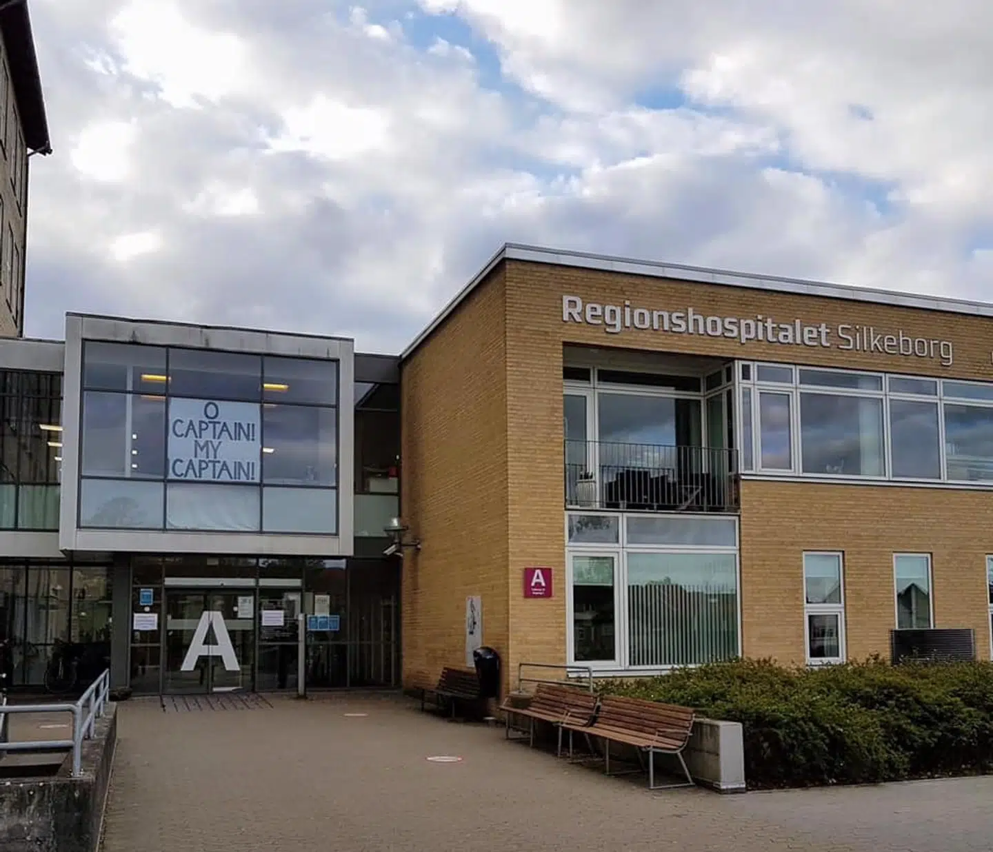 Indgangen til Silkeborg Sygehus, hvor de ansatte har hængt et banner op i vinduet. Teksten henviser til filmen 'Døde Poeters Klub', hvor en gruppe elever protesterer over en højt elsket lærers fyring ved at stille sig op på bordene en efter en med ordene: 'O Captain! My Captain'. En scene, lægerne på Regionshospitalet Silkeborg, spillede for Hospitalsledelsen til et møde i kølvandet på afskedigelsen, hvorefter de forlod lokalet. (Privatfoto)