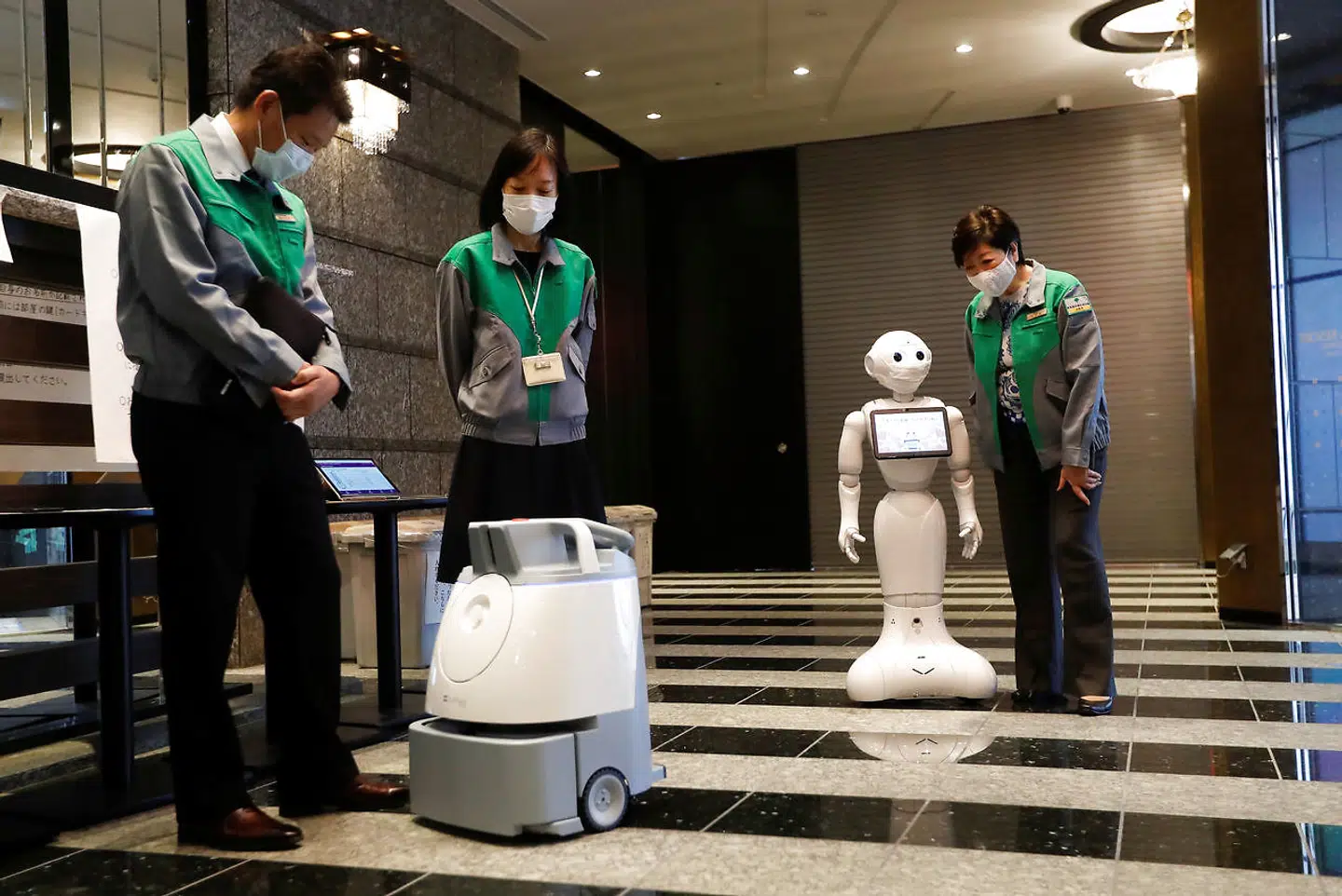 Tokyos guvernør Yuriko Koike, th, inspicerer robotten 'Peber', som skal være med til at holde modet oppe hos patienterne, der er smittet med COVID-19.