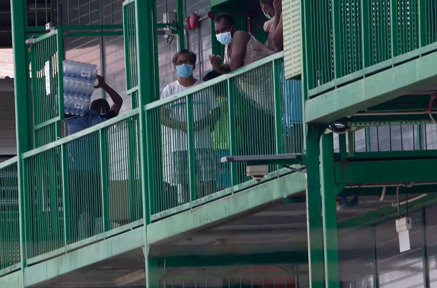 Her står nogen af de udenlandske arbejdere, der menes at have været medvirkende til eksplosionen i smittetilfælde, og trækker luft.