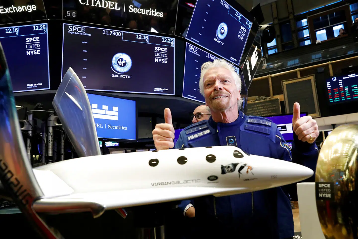 Richard Branson poserer på gulvet i New Yorks Stock Exchange med en model af sit rumskib, Virgin Galactic.