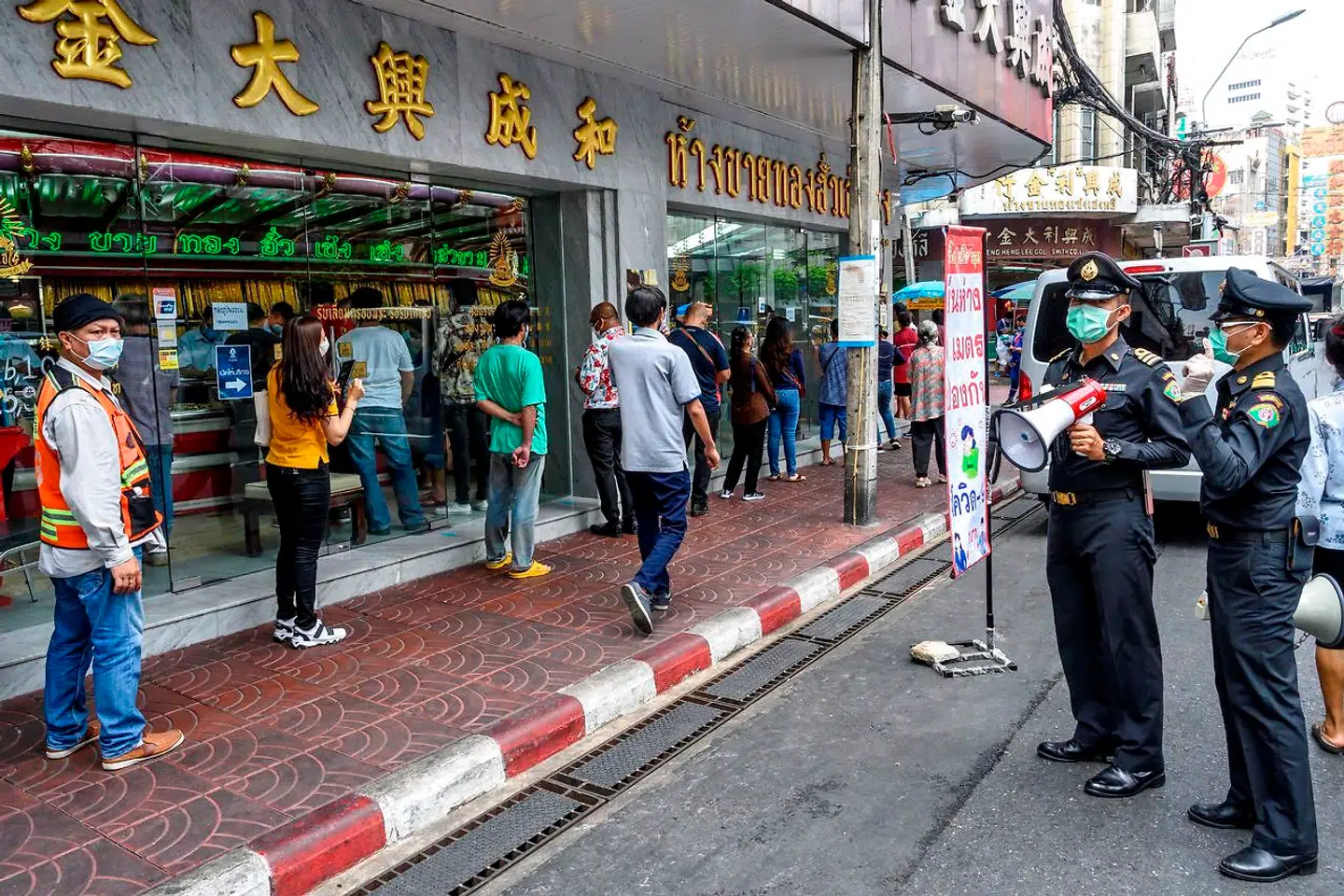 To politifolk holder øje med folk, der står i kø for at komme ind til guldsmeden.