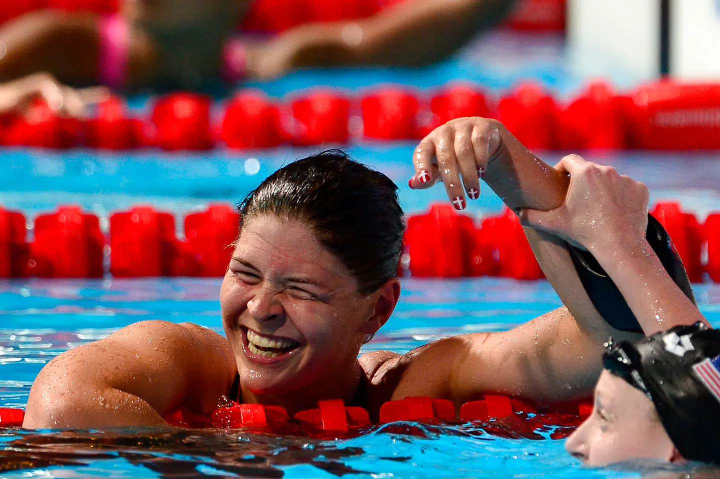 Guldvinderen ved VM i 2013, Katie Ledecky (th.), løfter anerkendende Lotte Friis' arm i vejret.