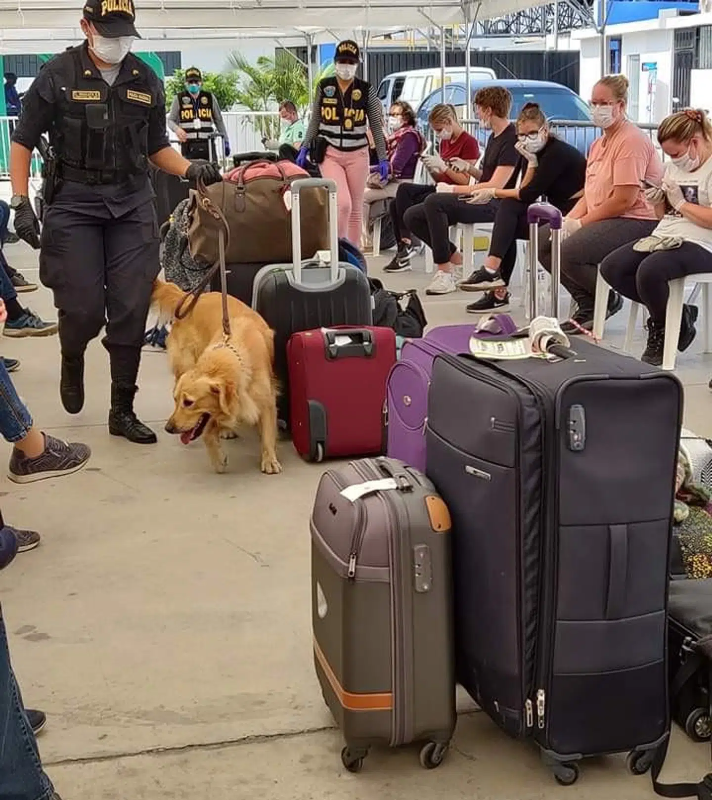 Politiet undersøger folks bagage i den interimistiske, udendørs ventehal på landingsbanen.