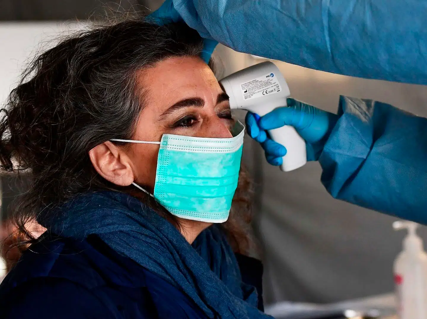 En sygeplejerske måler en kvindes temperatur i teltet uden for hospitalet, hvor personer med symptomer bliver testet.