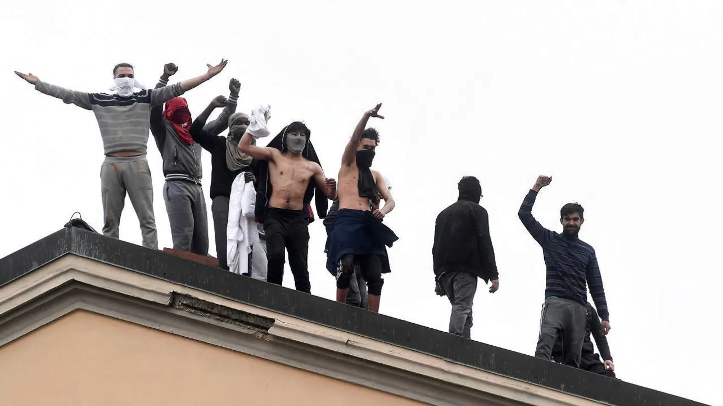 Vrede Indsatte står på taget af det italianske fængsel under mandagens oprør.