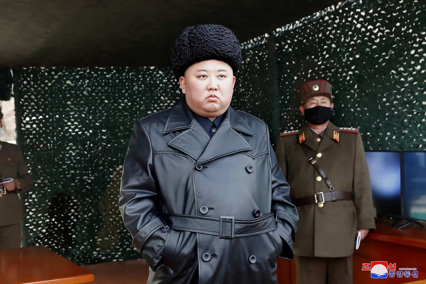Kim Jong Un ser på missitesten, men militærpersonen i baggrunden bærer en ansigtsmaske.