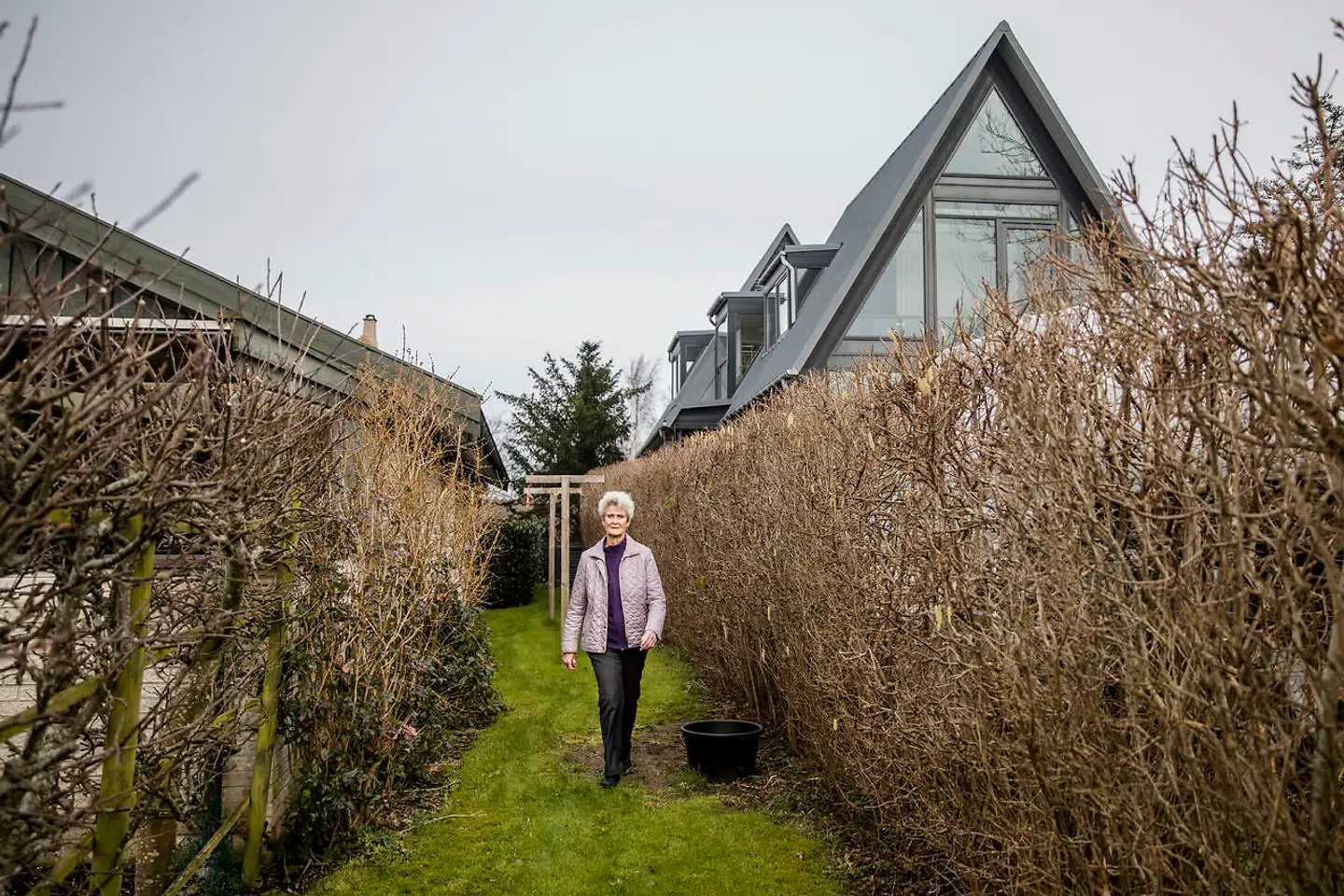 Birthe Engesgaard går i sin have i Gilleleje. Naboens hus til højre er både for højt og for tæt på skel.