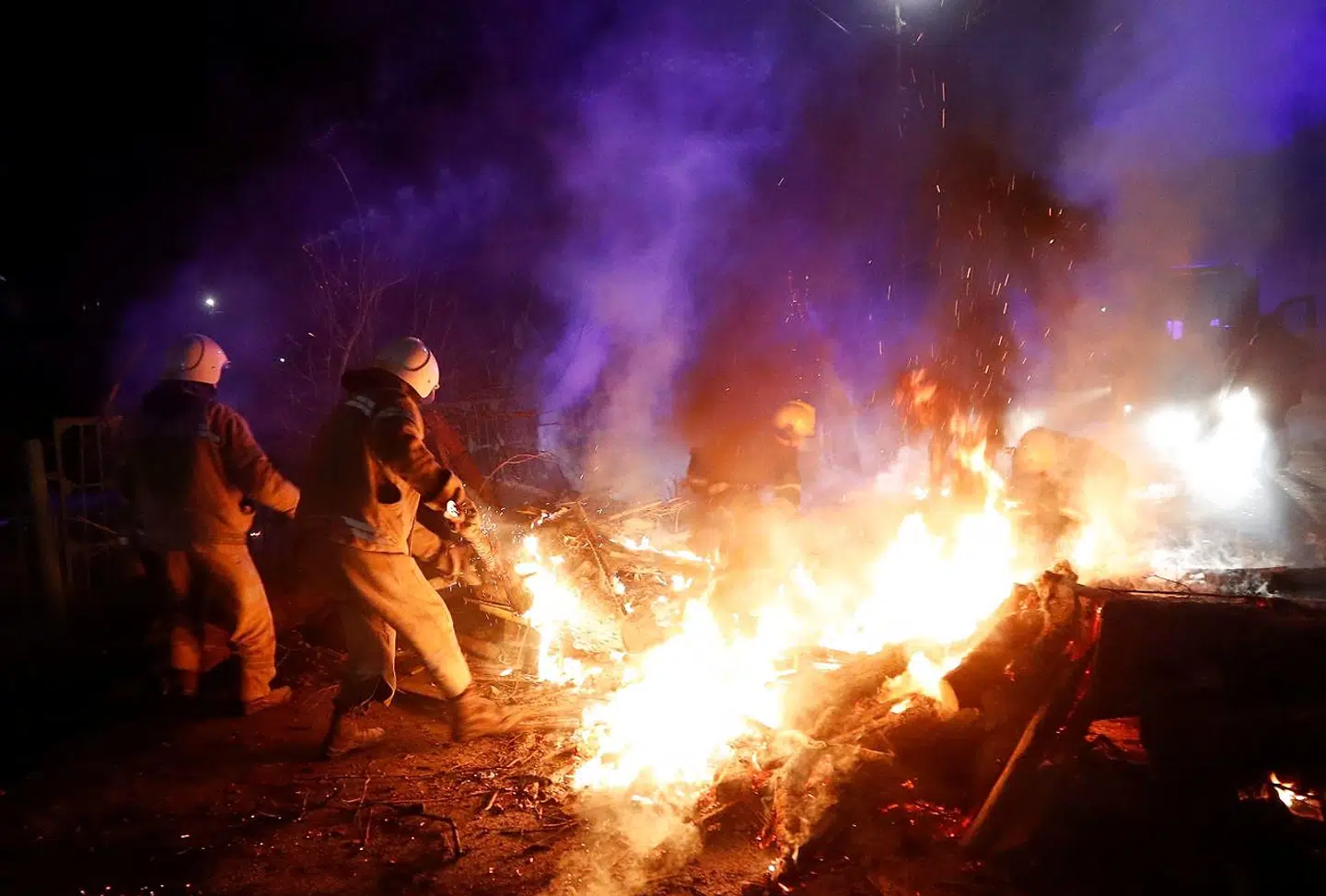 Ukrainske brandfolk fjerner noget brændende buskads, som demonstranterne har brugt som vejspærring.