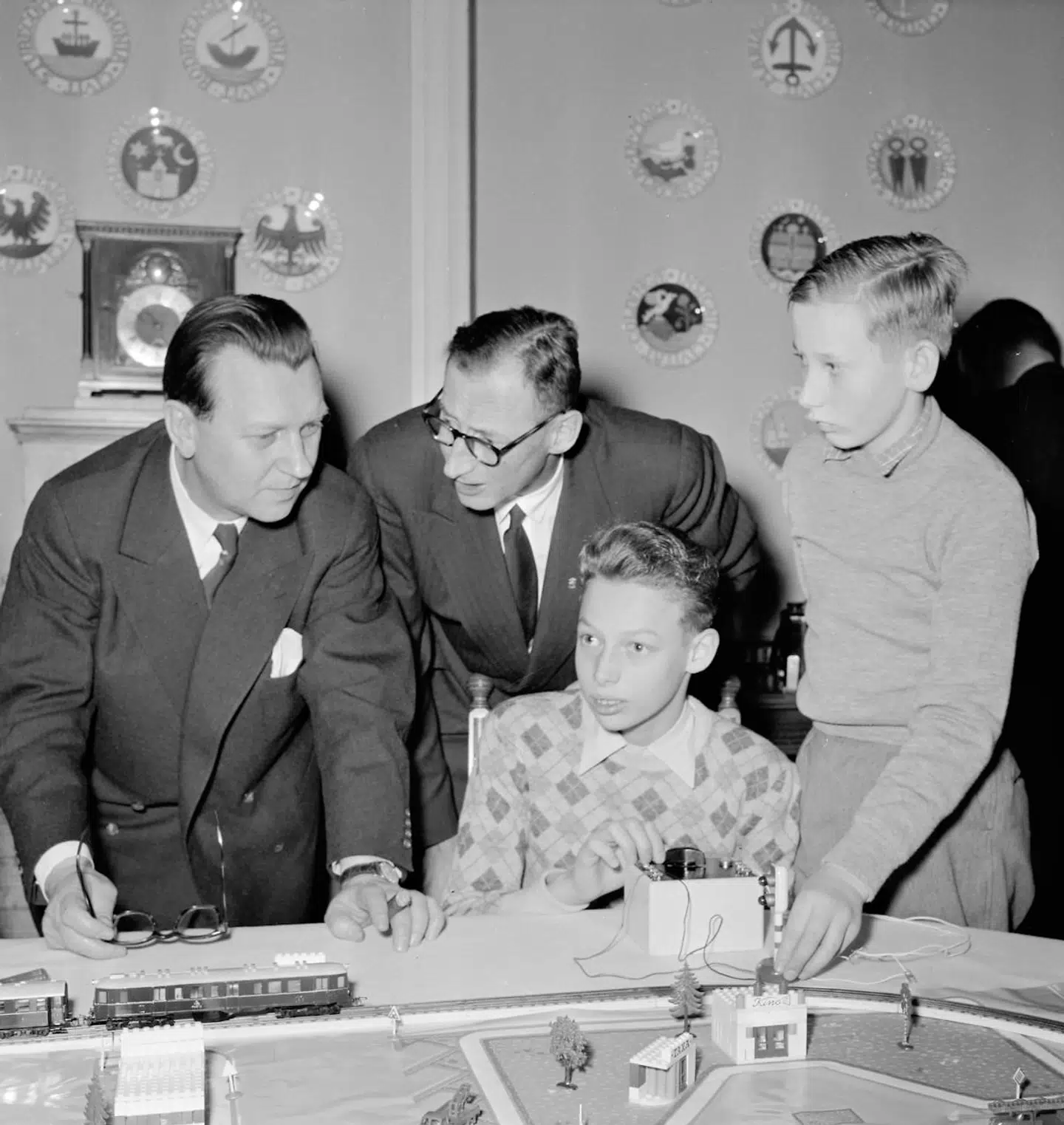 Modeltog har altid været et hit for drenge – tilsyneladende også for prins Ingolf og hans lillebror, prins Christian. De ses her sammen med statsminister H.C. Hansen samt deres far, arveprins Knud.