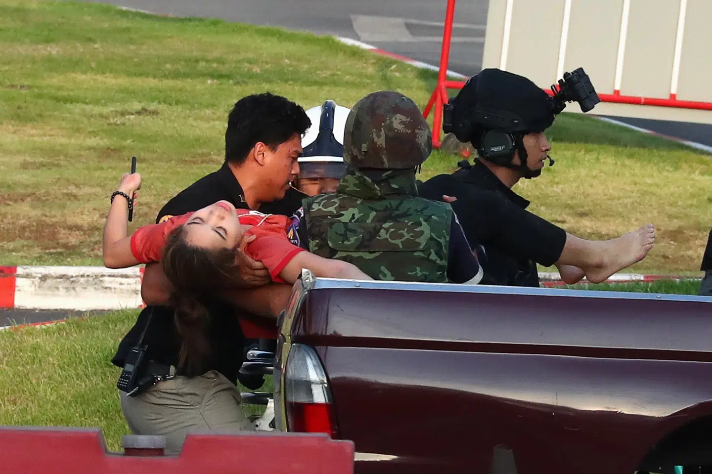 Sikkerhedsstyrker i Thailand hjælper en besvimet kvinde ud fra det shoppingcenter, hvor en soldat lørdag gik amok og skød omkring sig. Andre billeder viser kvinden løbe ud af shoppingcenteret sammen med betjente. Athit Perawongmetha/Reuters