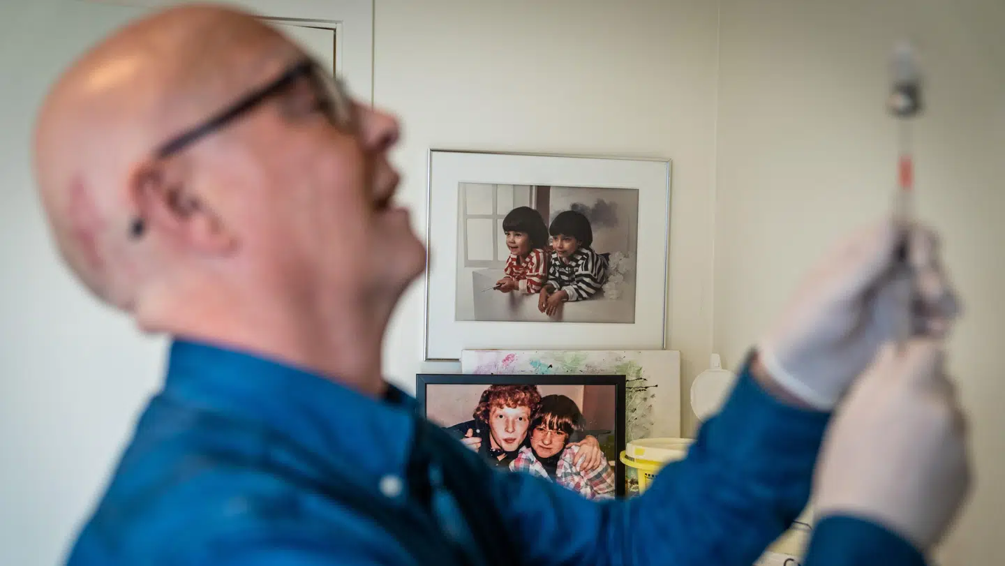 Henning i færd med at klargøre parenteral ernæring. I baggrunden ses et foto af Hennings to døtre og et foto af ham selv og hustruen fra dengang de var unge. Foto: Rasmus Laurvig/Byrd.