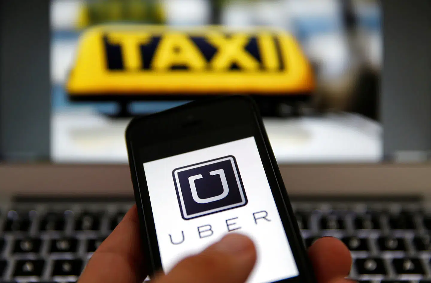 FILE PHOTO: An illustration picture shows the logo of car-sharing service app Uber on a smartphone next to the picture of an official German taxi sign in Frankfurt, September 15, 2014. REUTERS/Kai Pfaffenbach/File Photo