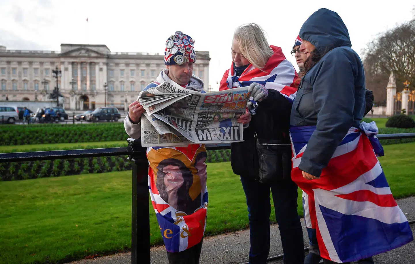 En gruppe royalister har taget opstilling foran Buckingham Palace i London, hvor den royale sag kaldes 'Megxit' på forsiden af aviserne.