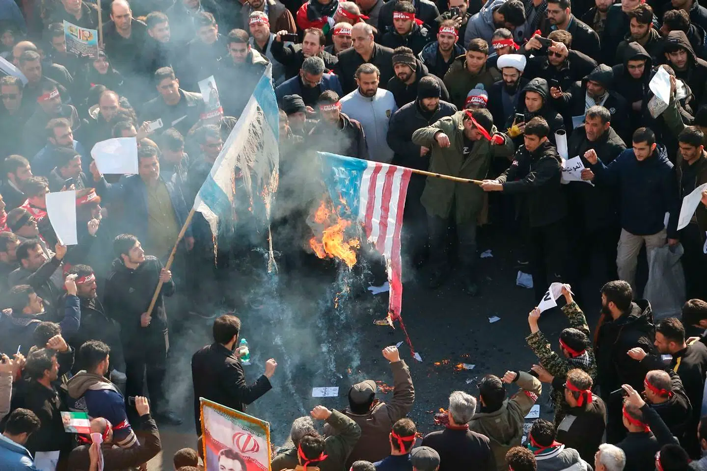 Iranere sætter ild til amerikanske og israelske flag under demonstrationer ved begravelsesceremonien af general Qasem Soleimani i Teheran. ATTA KENARE / AFP.