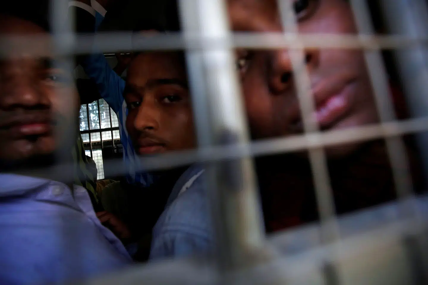 Indefra en politransport ser unge mislimske mænd fra Rohingya-stammen til, mens de nærmer sig retten i byen Pathein,