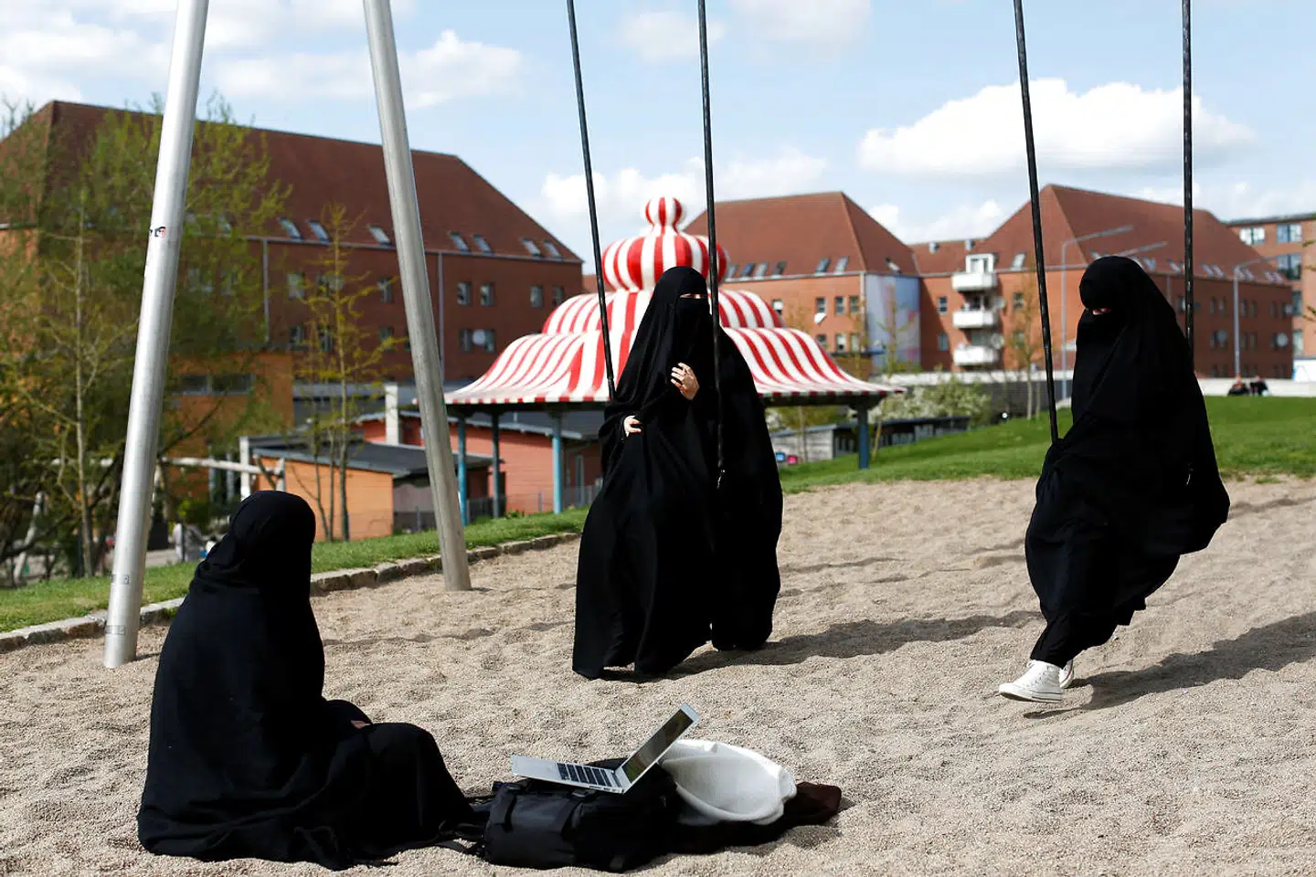 Zaynab (C) who lives in Mjolnerparken, a housing estate that features on the Danish government's "Ghetto List", sits with her friends Amira and Sabrina in Superkilen, a recently designed urban renewal park that runs beside Mjolnerparken, in Copenhagen, Denmark, May 3, 2018. REUTERS/Andrew Kelly SEARCH "DENMARK GHETTO" FOR THIS STORY. SEARCH "WIDER IMAGE" FOR ALL STORIES. THE IMAGES SHOULD ONLY BE USED TOGETHER WITH THE STORY - NO STAND-ALONE USES. TPX IMAGES OF THE DAY
