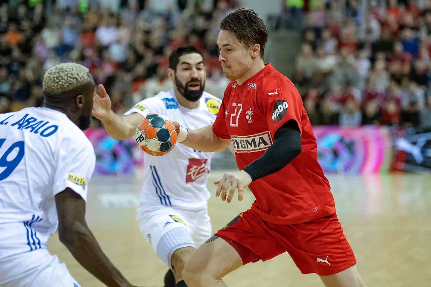 Danmarks Michael Damgaard i duel med Frankrigs Luc Abalo (19) samt Nikola Karabatic (13).