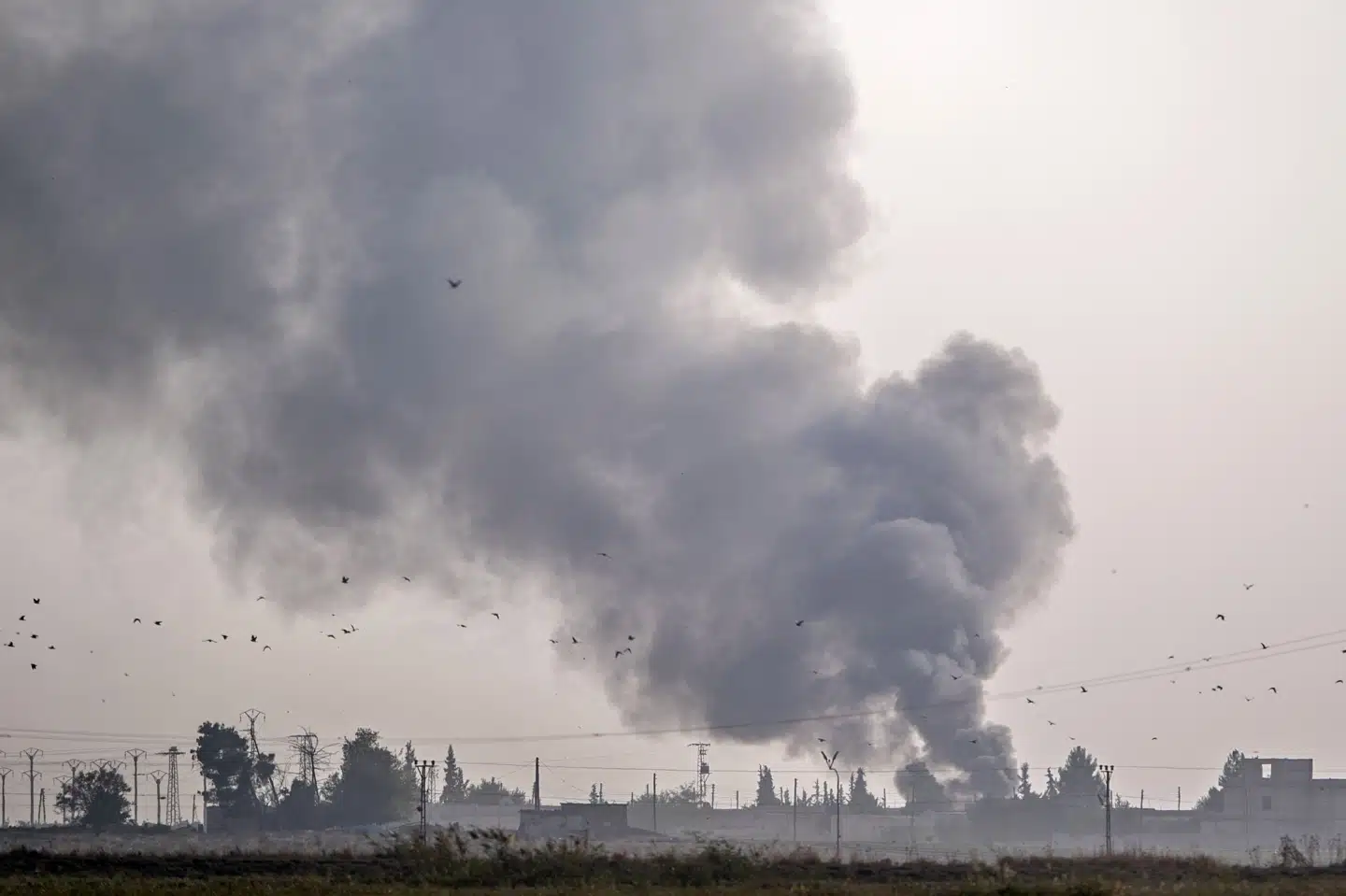 Røgskyer rejser sig over byen Tel Abyad i det nordlige Syrien, efter tyrkiske kampfly har bombet. Bulent Kilic/Ritzau Scanpix