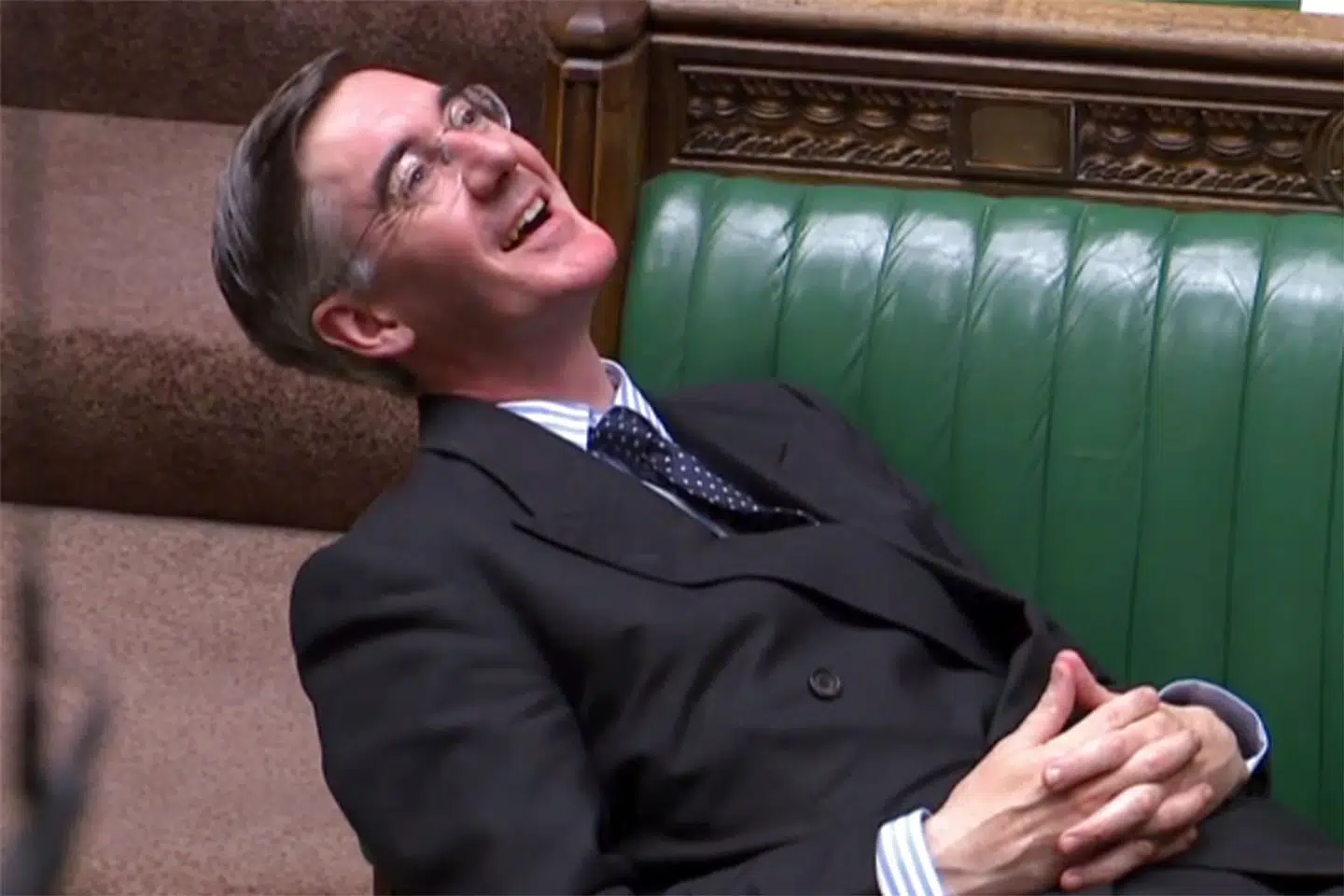 Jacob Rees-Mogg griner, da hans parlamentskollegaer beder ham sætte sig ordentligt op.