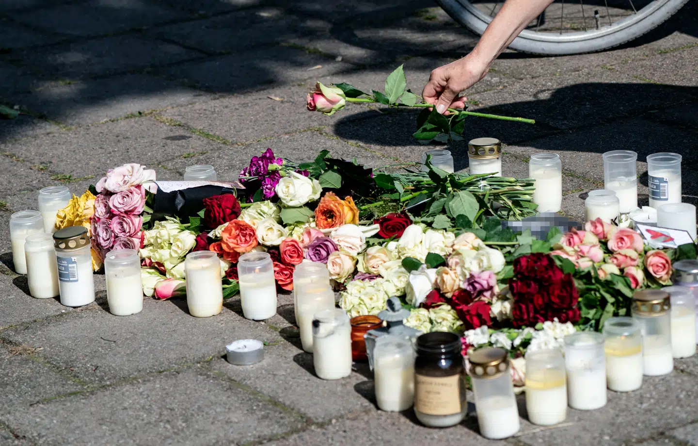 En kvinde lægger et lys på det sted, hvor den 31-årige mor mandag blev likvideret. (Foto: 50090 Johan Nilsson/TT/Ritzau Scanpix)