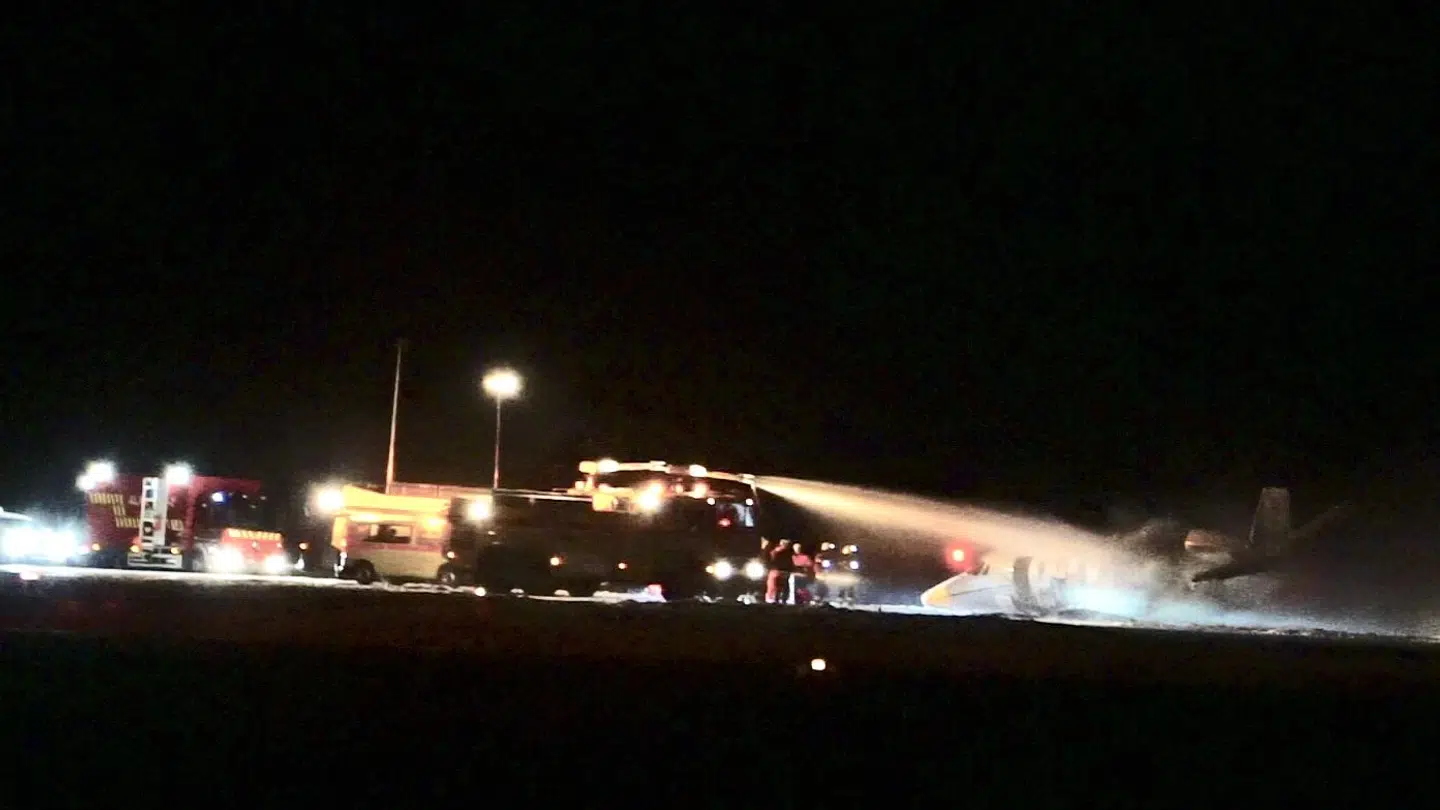 Brandvæsnet slukker her branden, der opstod på flyet efter landingen.